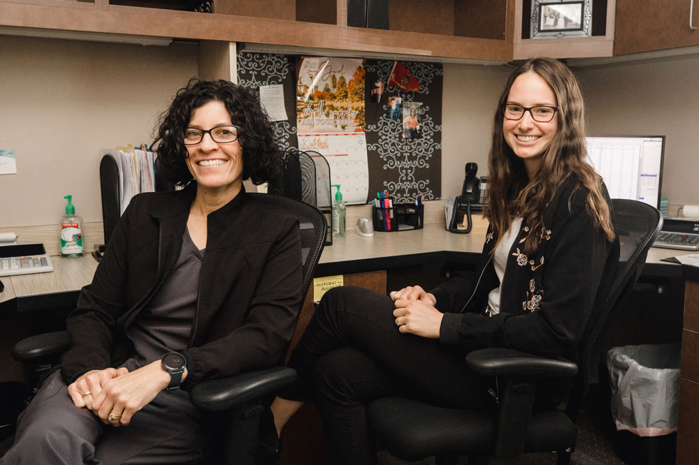 Two women, smiling and sitting at a desk